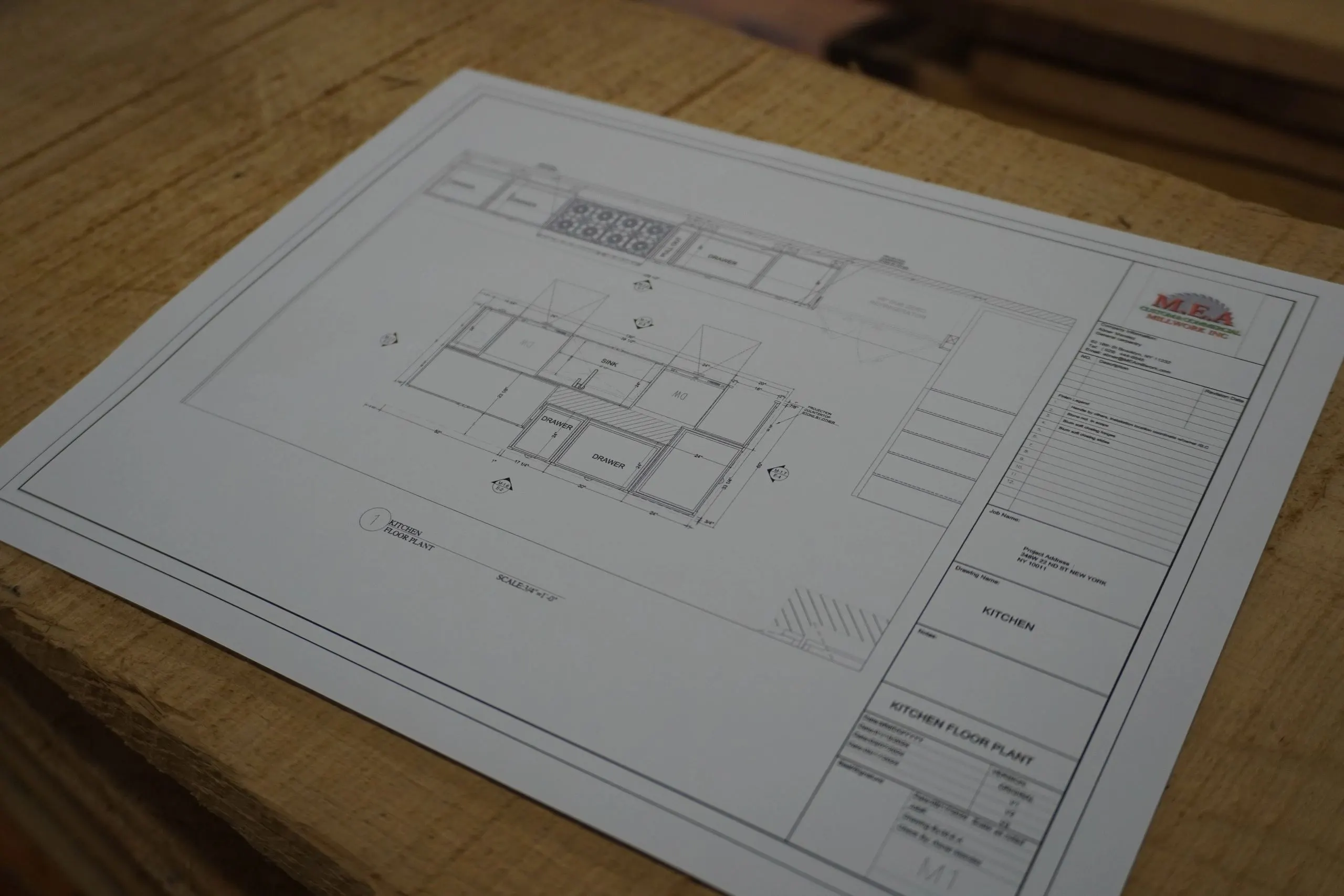Architectural drawing for a millwork project resting on a stack of lumber in the shop