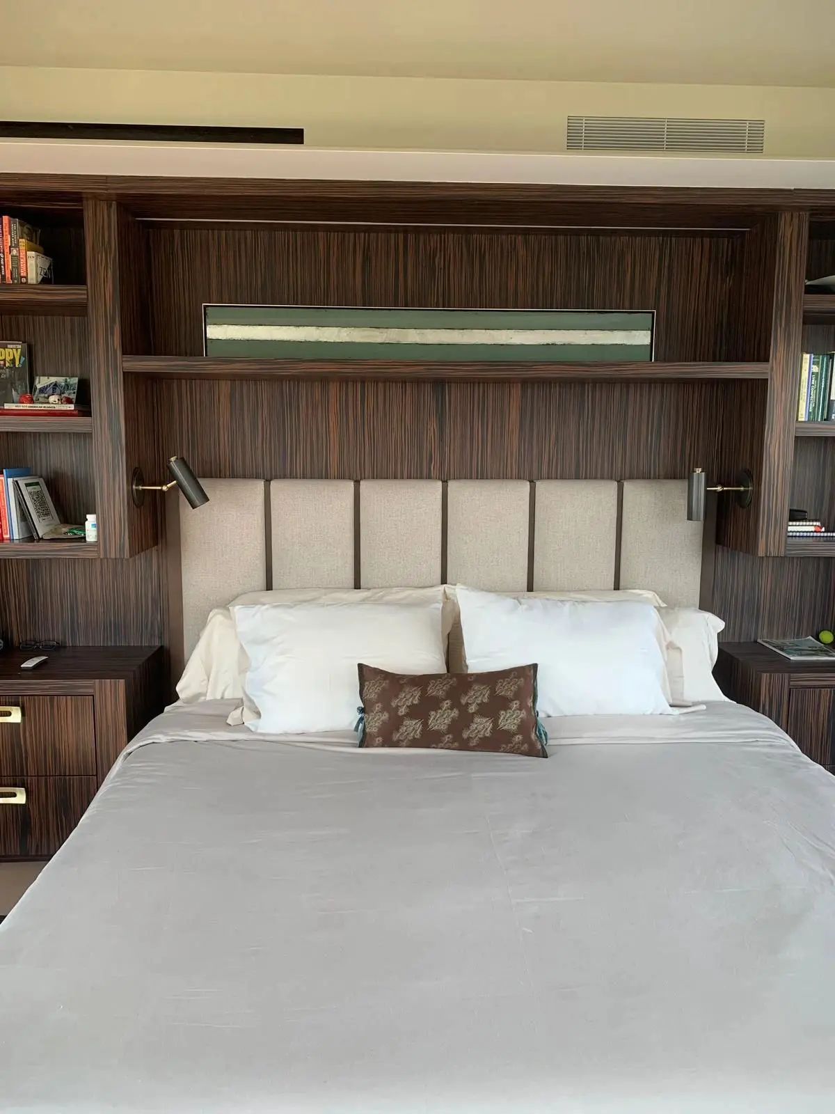 Bedroom wall of wood paneling, open shelving, and an upholstered headboard
