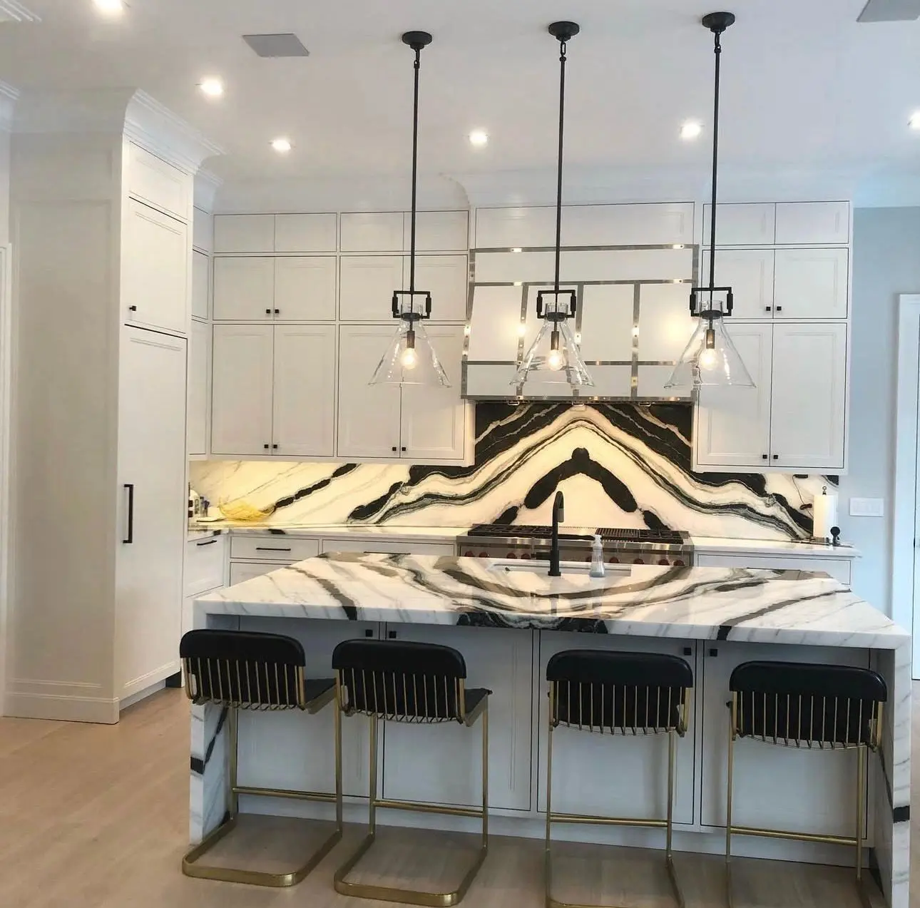 White kitchen cabinetry with a book-matched marble island