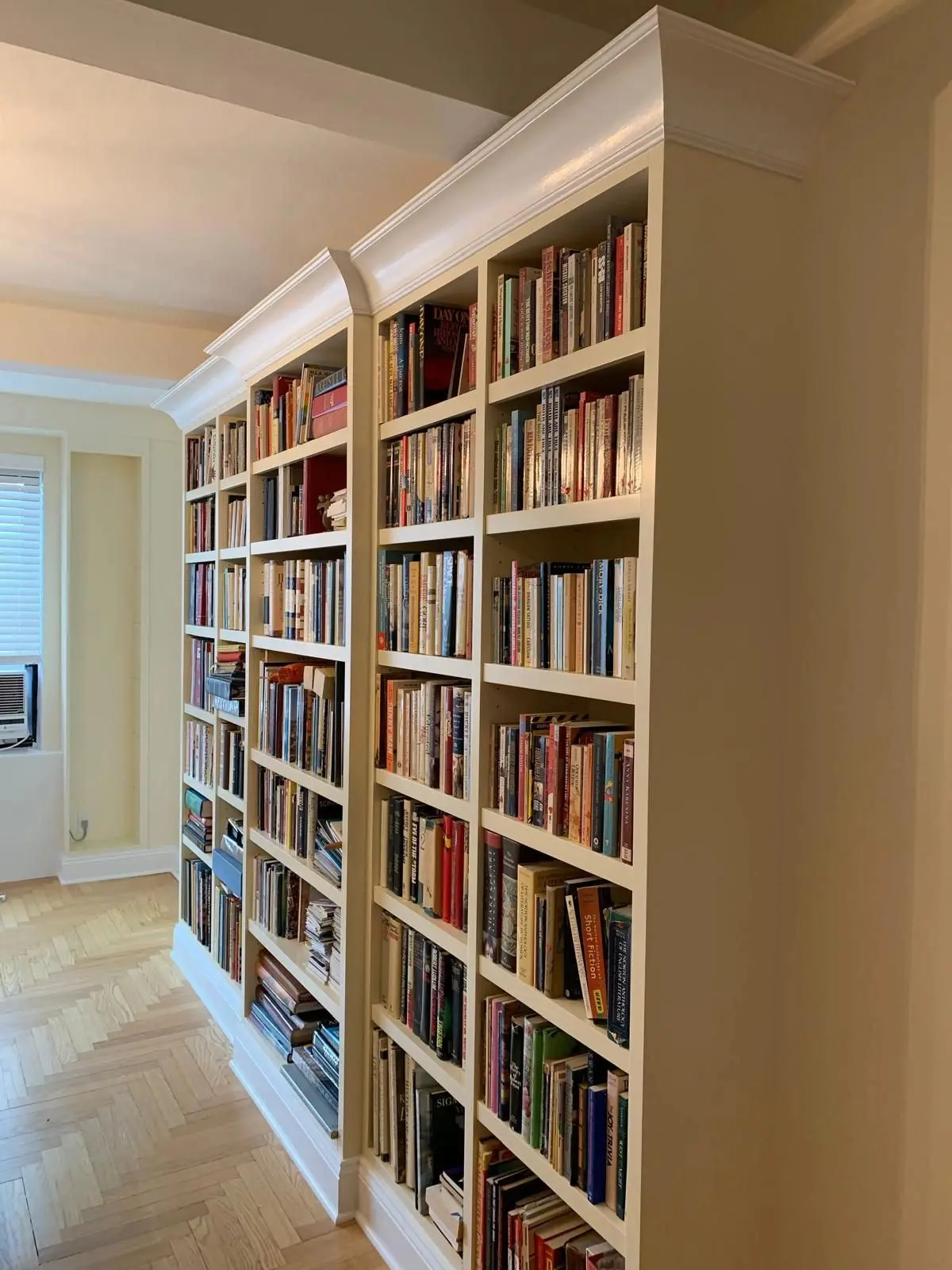 Floor-to-ceiling white built-in bookcases with crown molding