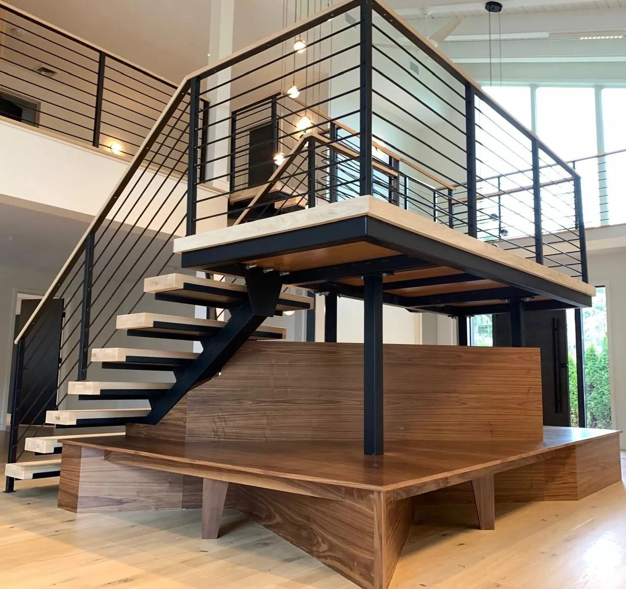 Floating staircase and walnut-clad platform with black steel railings